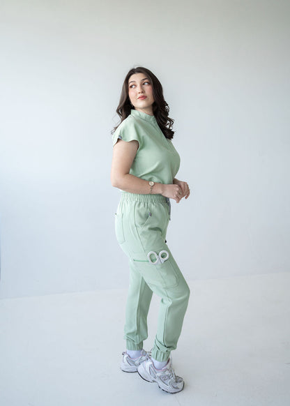 Woman wearing  mint green scrubs against a white background